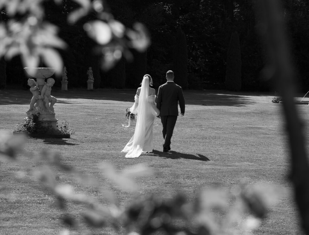 Braut und Bräutigam laufen über eine Wiese in Heroldsbach Schloss Thurn.