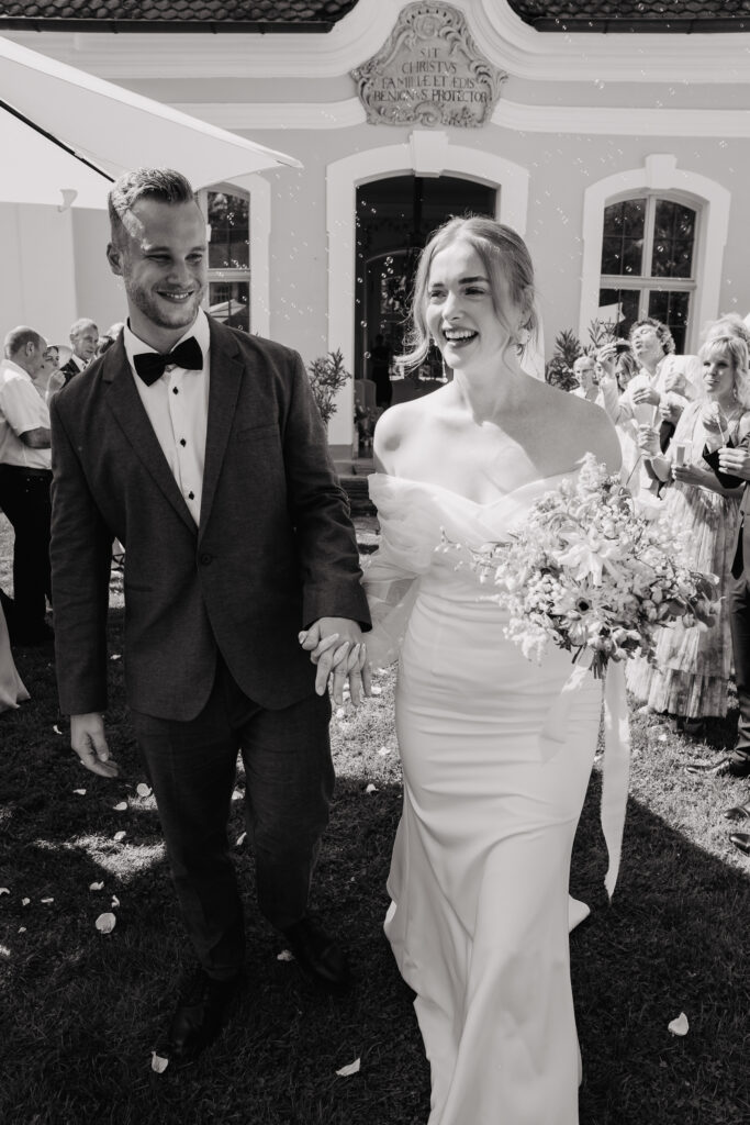 Braut und Bräutigam verlassen lachend das Standesamt in Heroldsbach im Schloss Thurn.