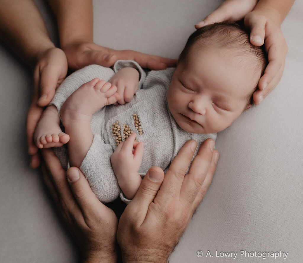 Neugeborenes Baby wird von den Händen seiner Familie gehalten in Forchheim.